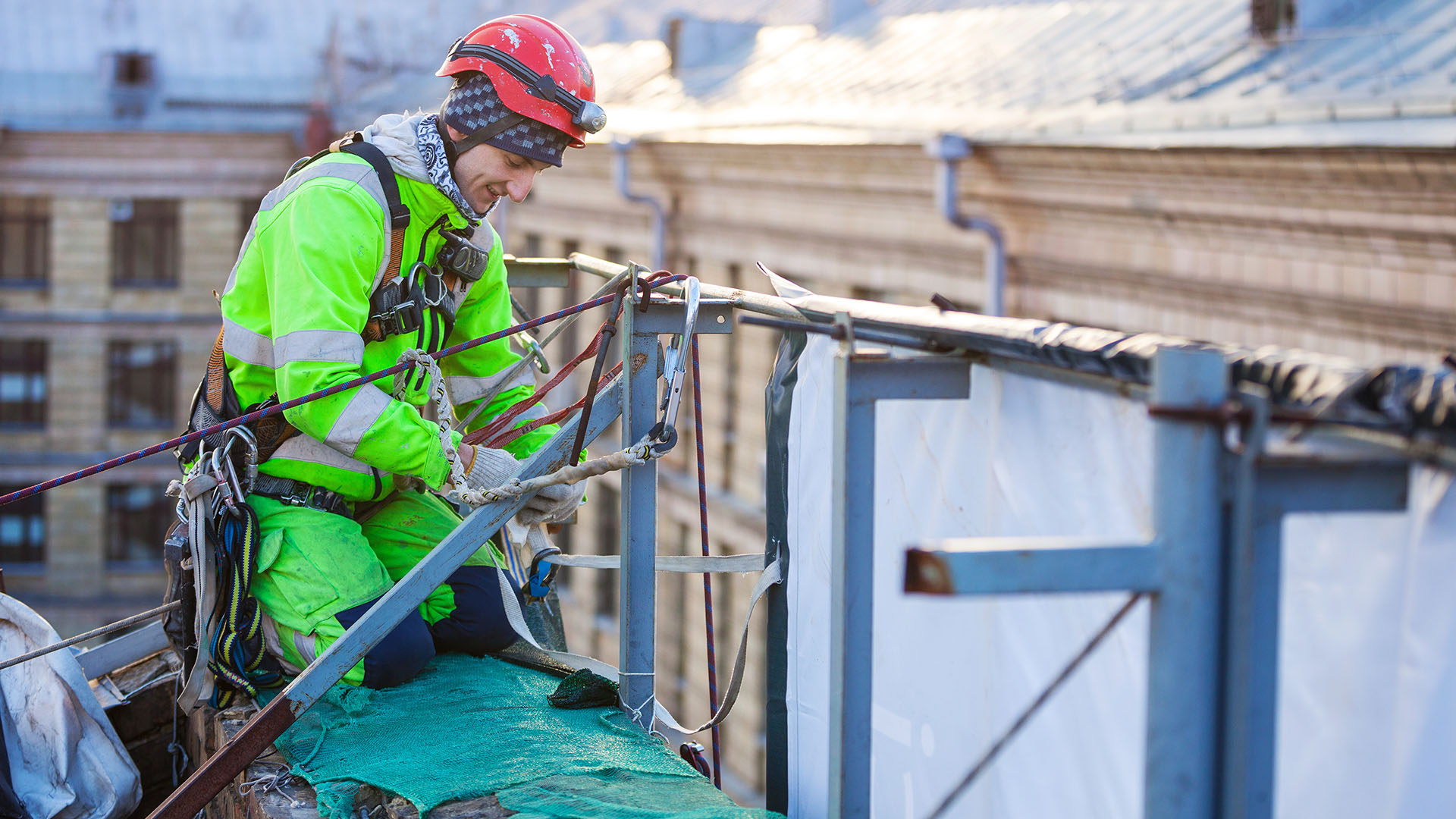 Man op dak in veiligheidskleding en aangelijnd aan het werk