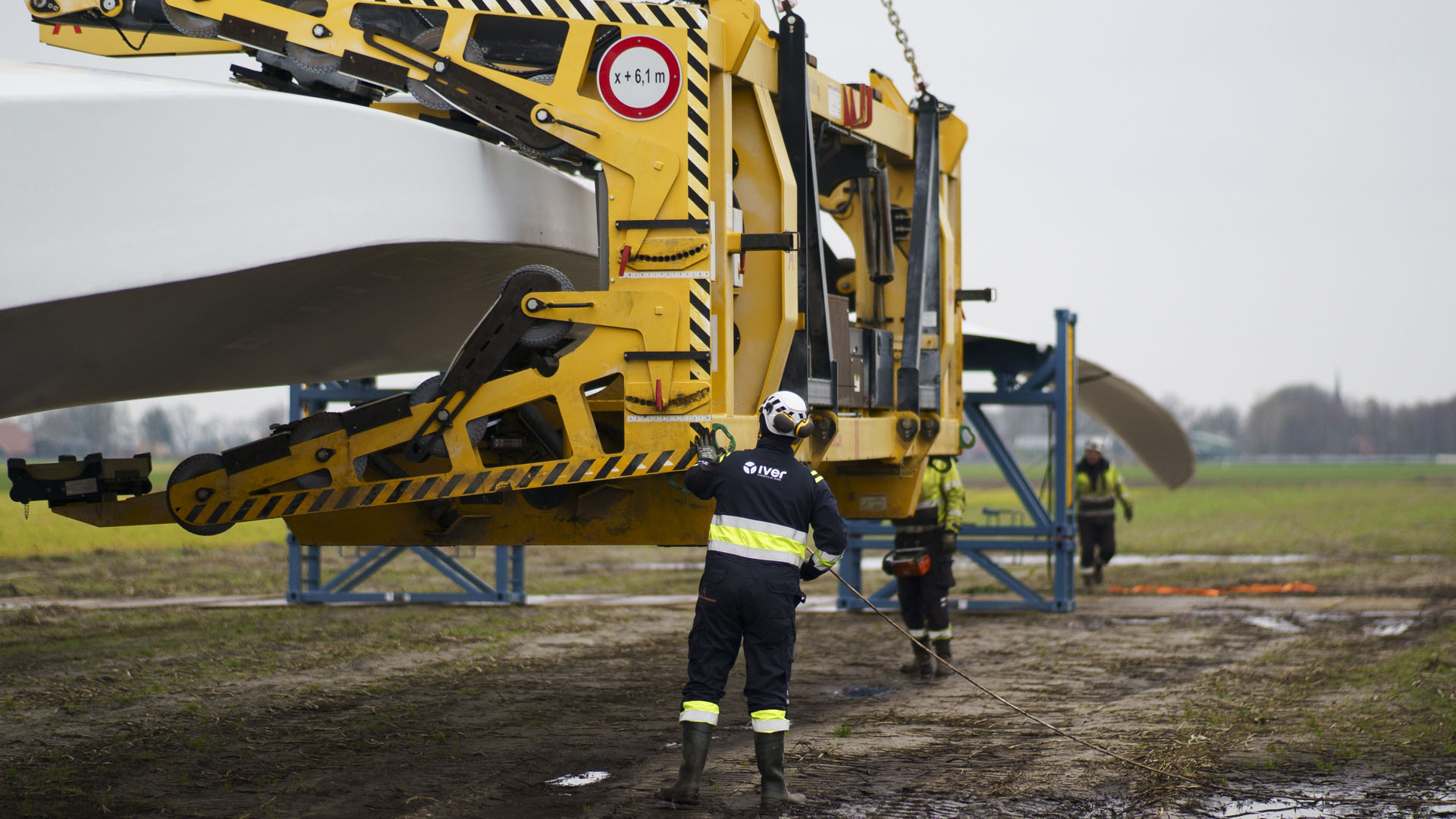 Mannen in werkkleding bij een grote machine in een weiland (van het bedrijf Iver)