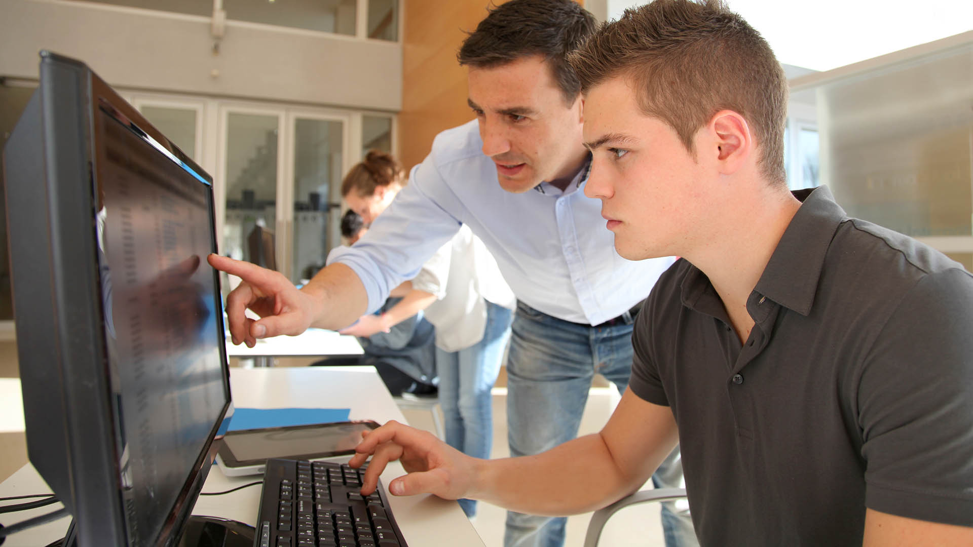 Leraar en student werken op computer