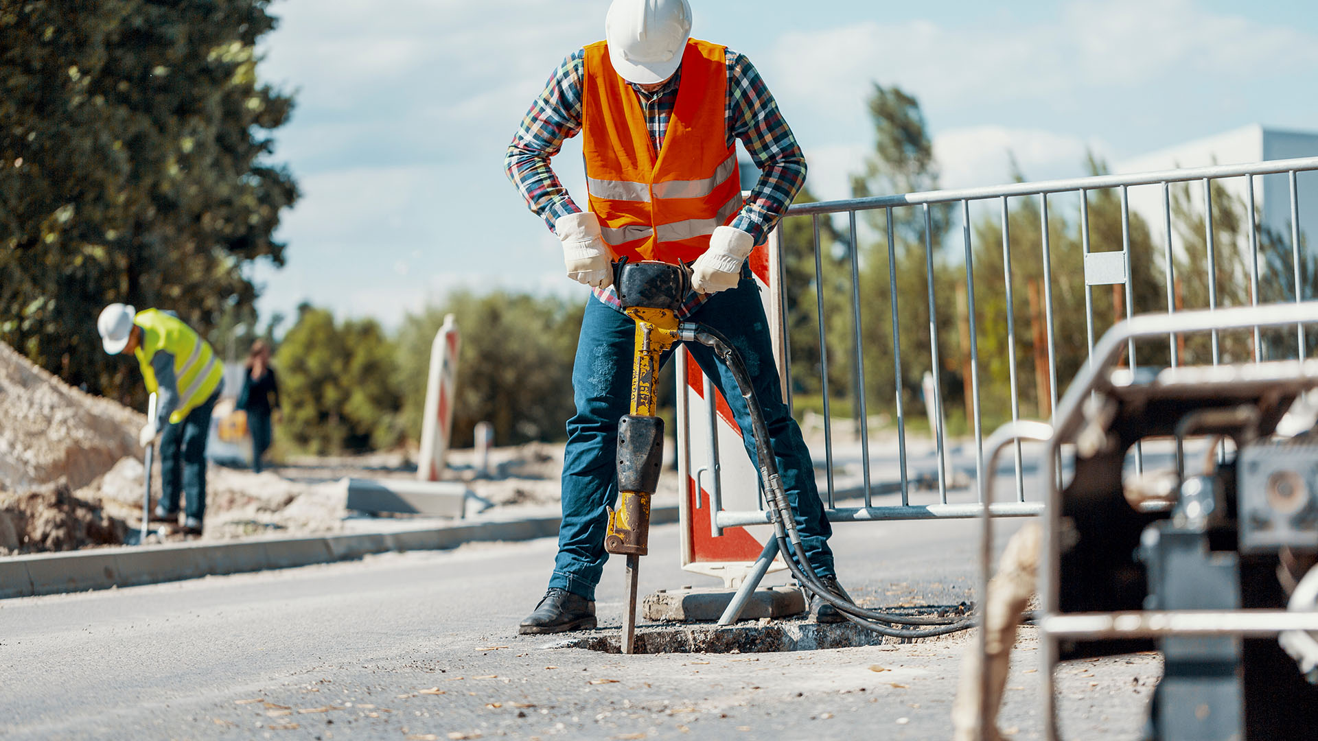 Werknemers met veiligheidskleding en helm aan het werk met trilboor