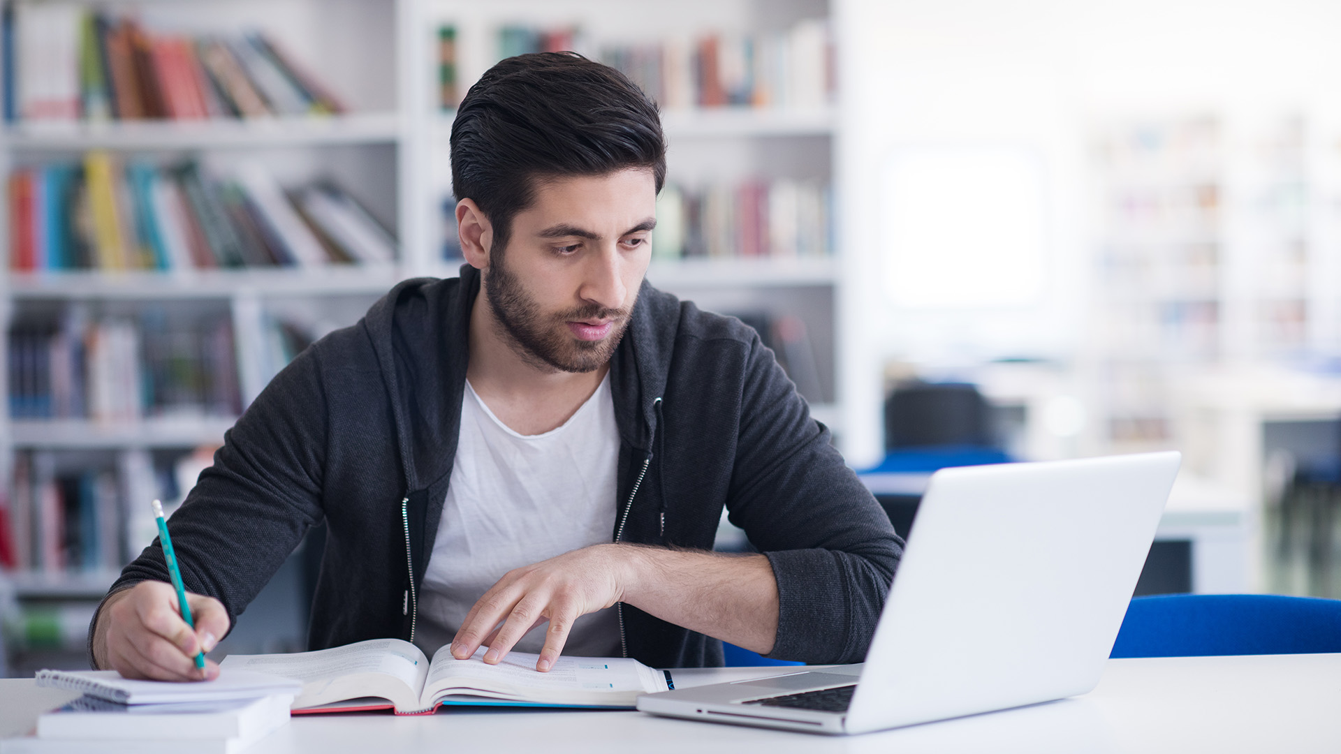 Jongen aan de studie achter laptop en boeken