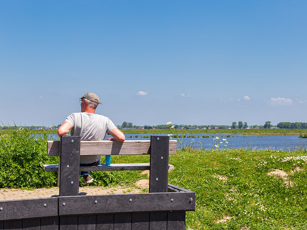 Man op bankje geniet van natuur